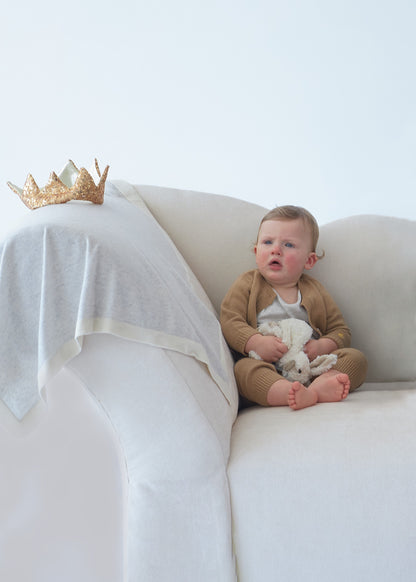 Couverture bébé grise en cachemire posée sur un canapé BOTIBOTY